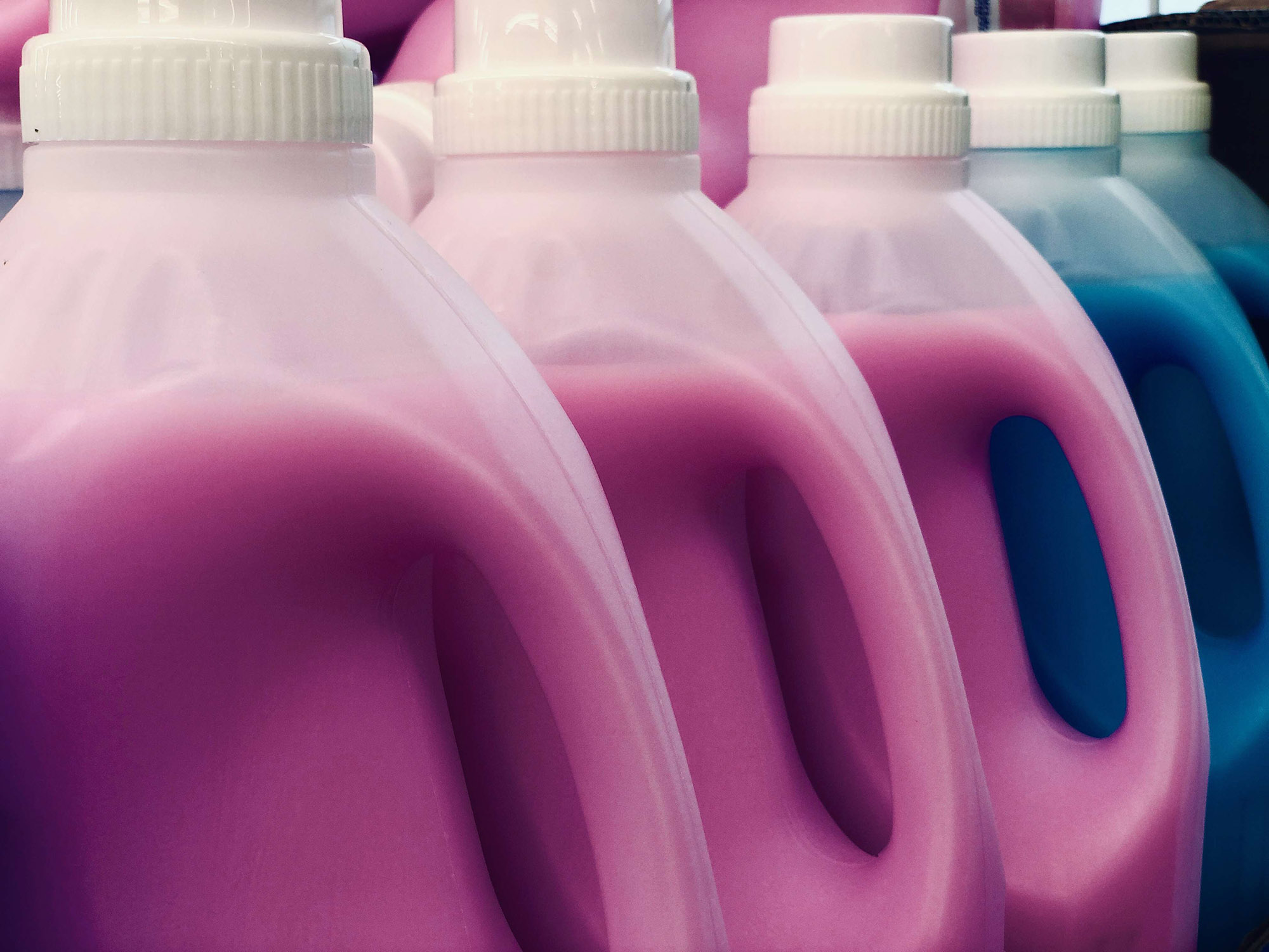 Different colored laundry detergents in plastic bottles.