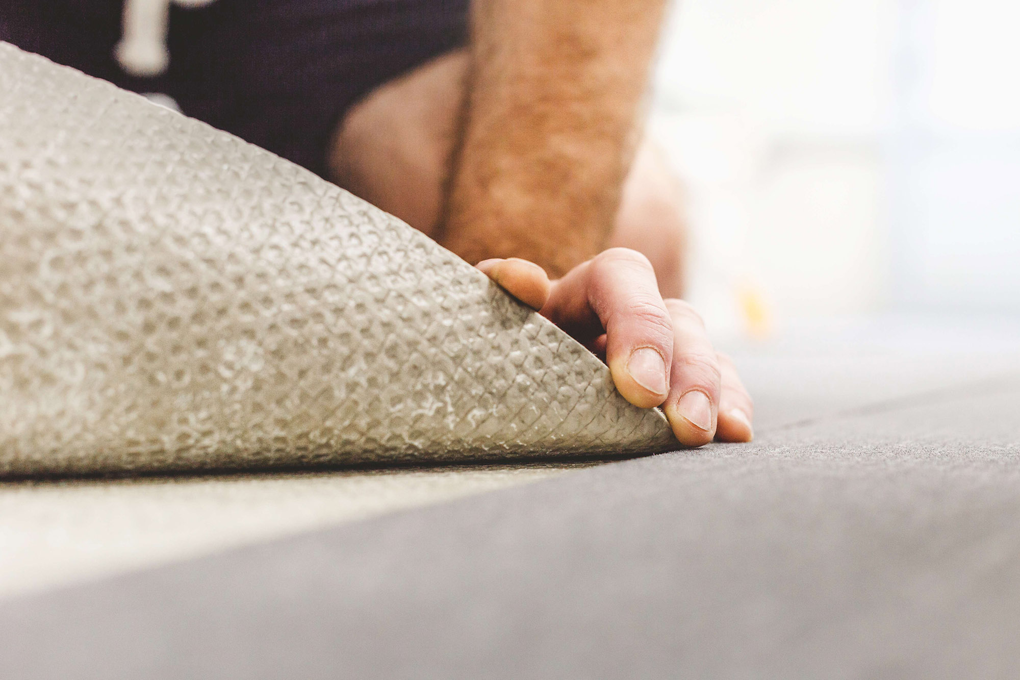 Hands laying down carpet.